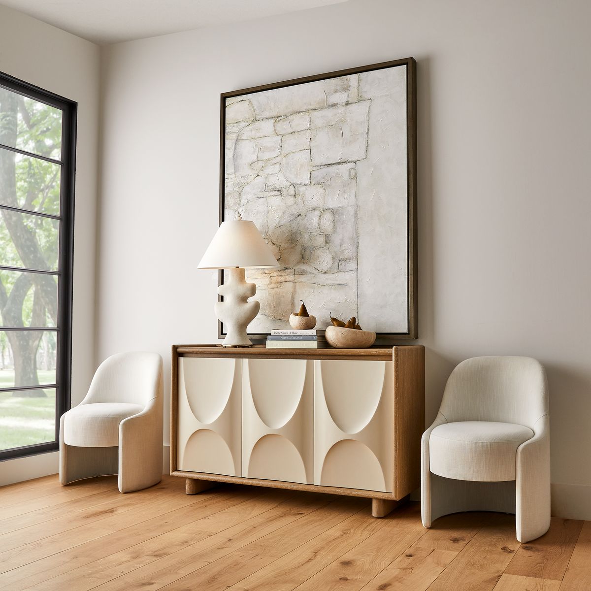 Travertine bowls styled on a carved wood sideboard in an airy neutral living room — Rachel Blindauer travertine collection