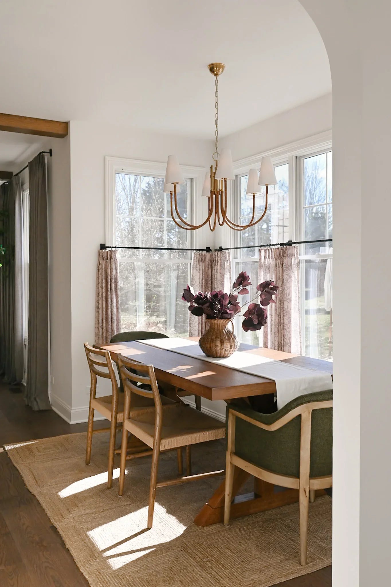 Marais Chandelier installed above a sunlit dining table, brass sculptural frame with linen shades in a warm, editorial room setting