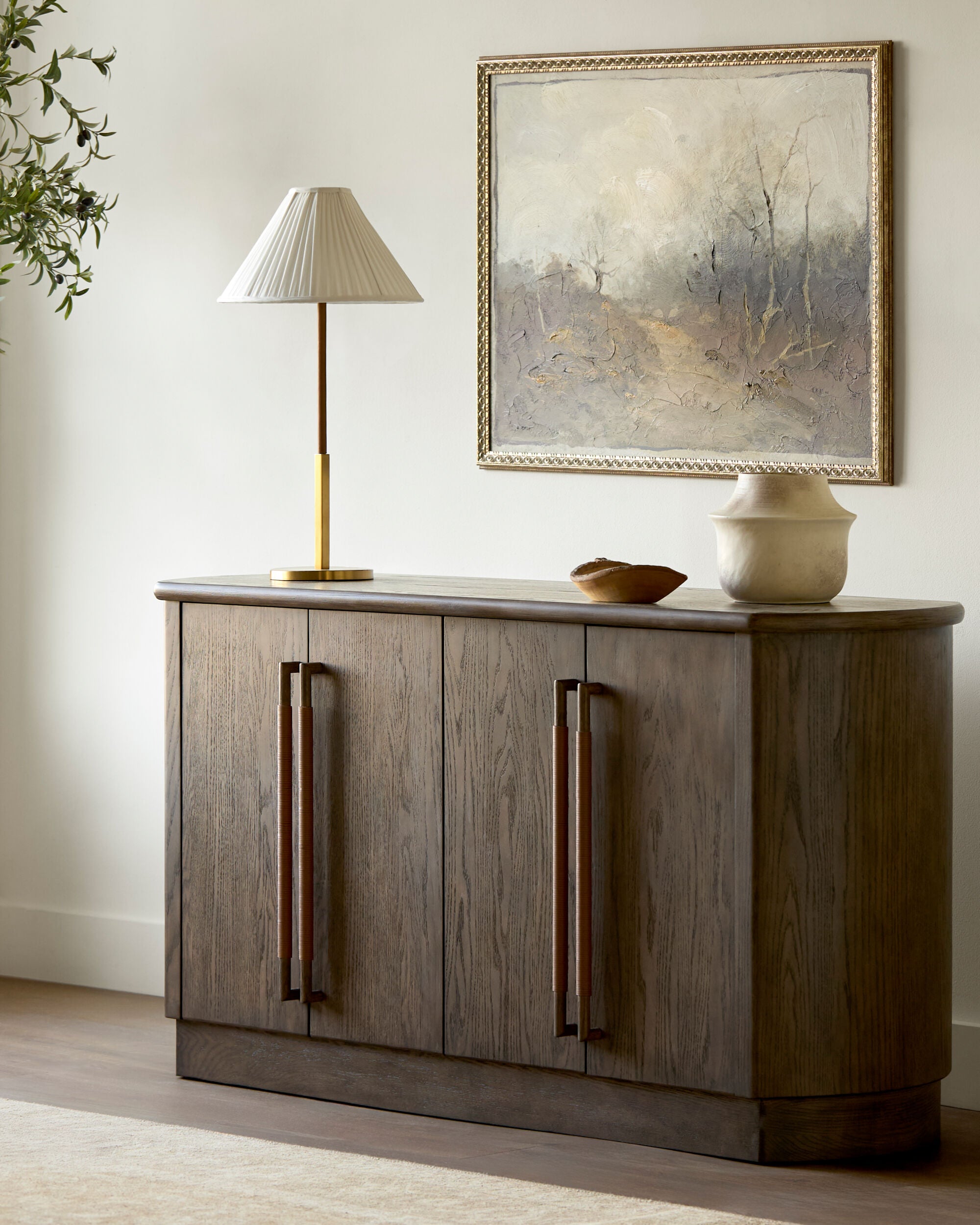 Aurelia Table Lamp — antiqued brass mid-century modern table lamp styled on a sideboard with art, one of Rachel Blindauer's favorites