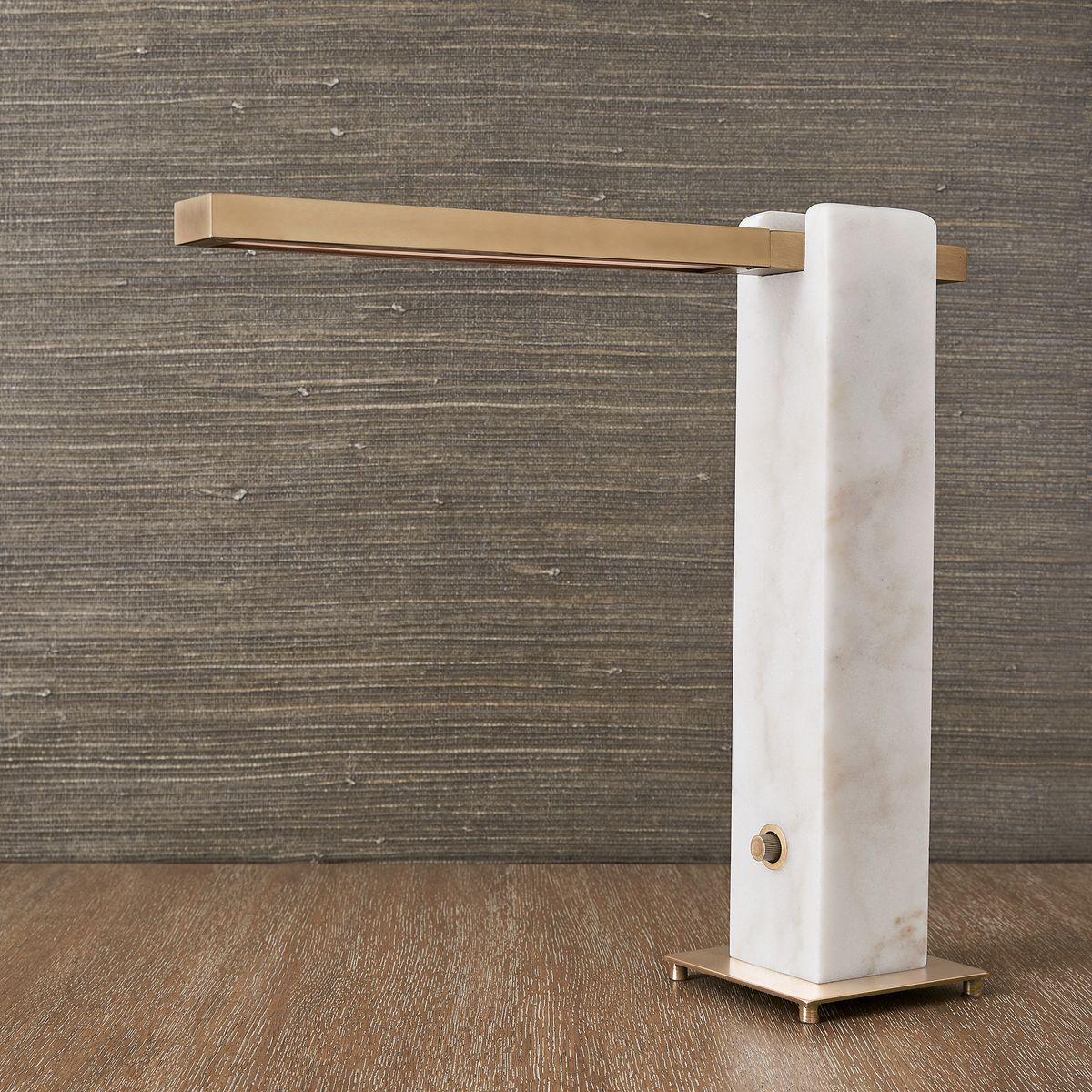 Modern table lamp with honed white marble base, antique brass arm, and pivoting LED light—sculptural and dimmable for desks, bedsides, or living spaces.