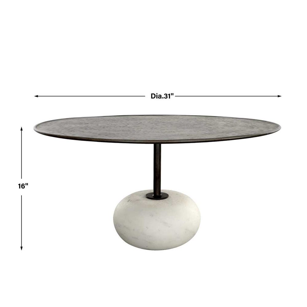 Round table with measurements on a white background. Round coffee table with hammered steel top and carved white stone base, styled in a sculptural modern living room with layered neutral textures.
