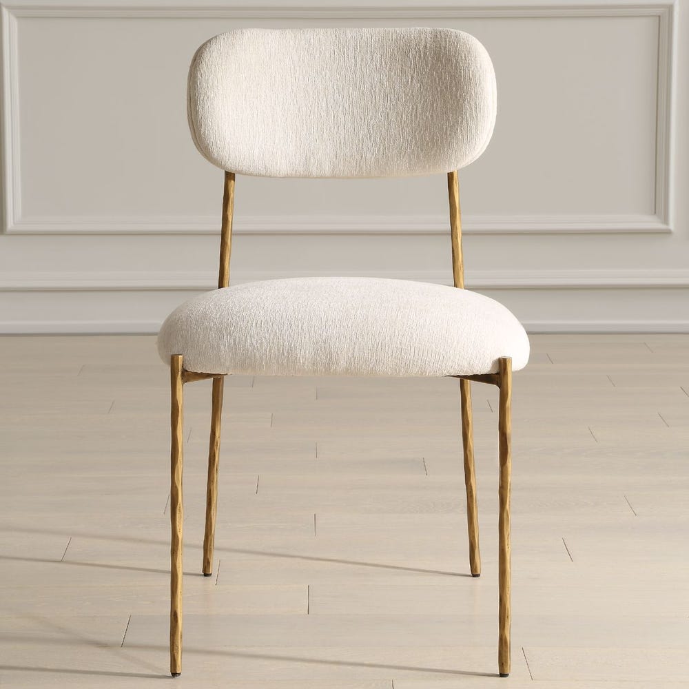 Sculptural iron dining chair with antique gold finish and floating off-white upholstered backrest.