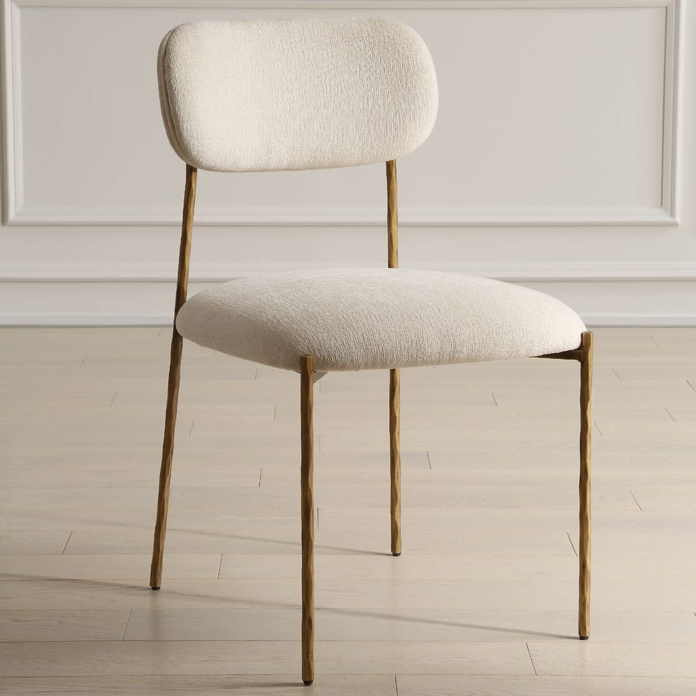 Sculptural iron dining chair with antique gold finish and floating off-white upholstered backrest.