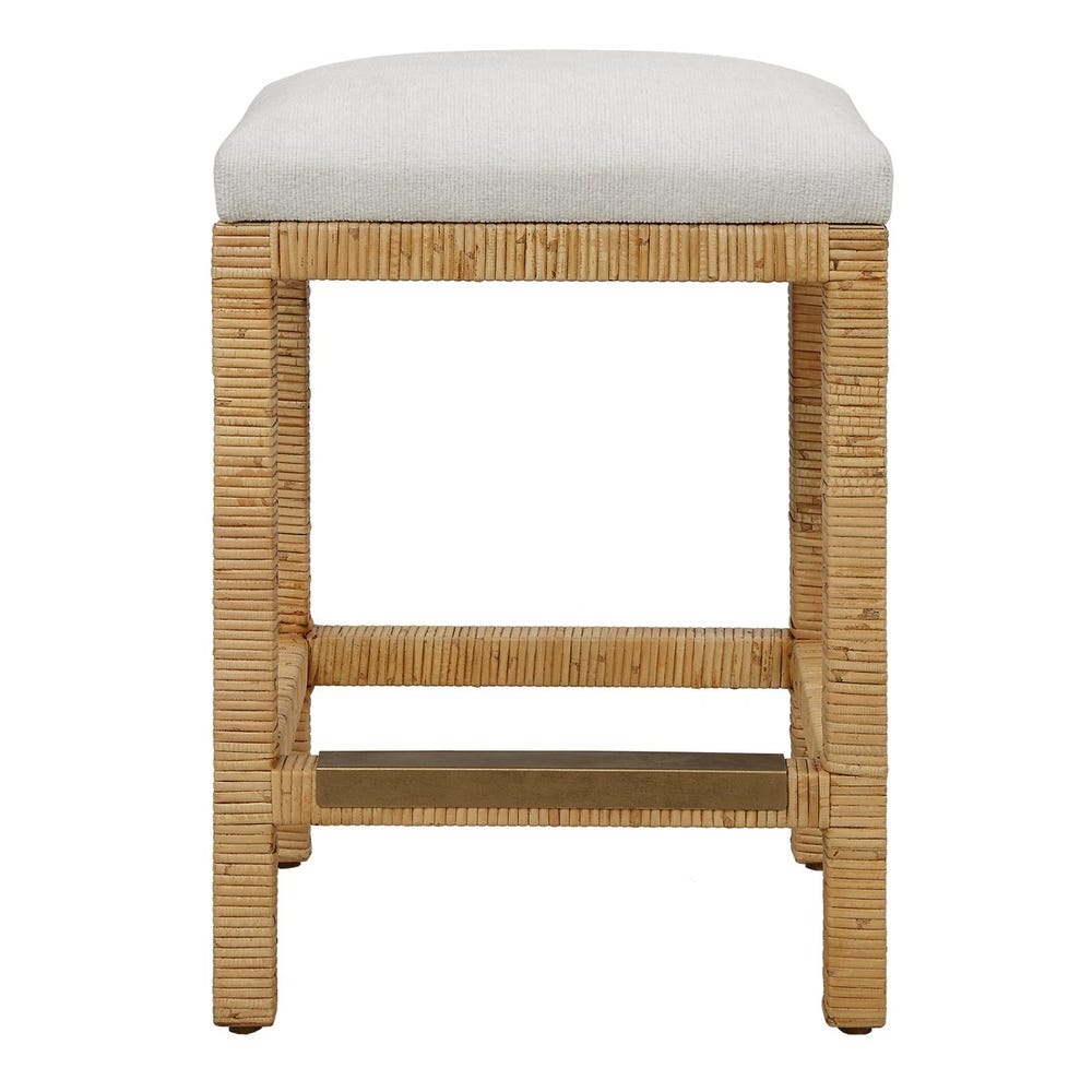 Handwoven rattan counter-height stool with off-white cushion and antique gold kickplate—coastal-inspired and refined.