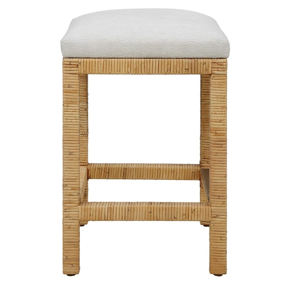 Handwoven rattan counter-height stool with off-white cushion and antique gold kickplate—coastal-inspired and refined.