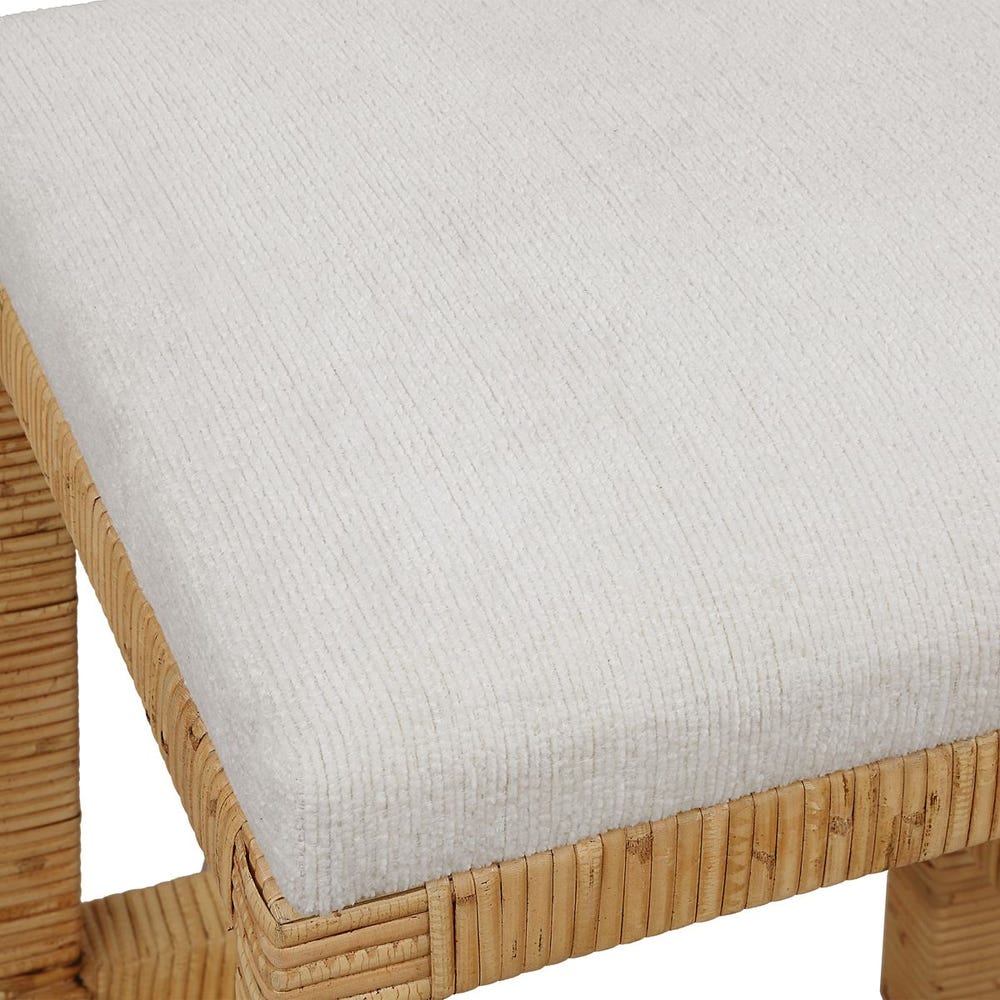 Handwoven rattan counter-height stool with off-white cushion and antique gold kickplate—coastal-inspired and refined.