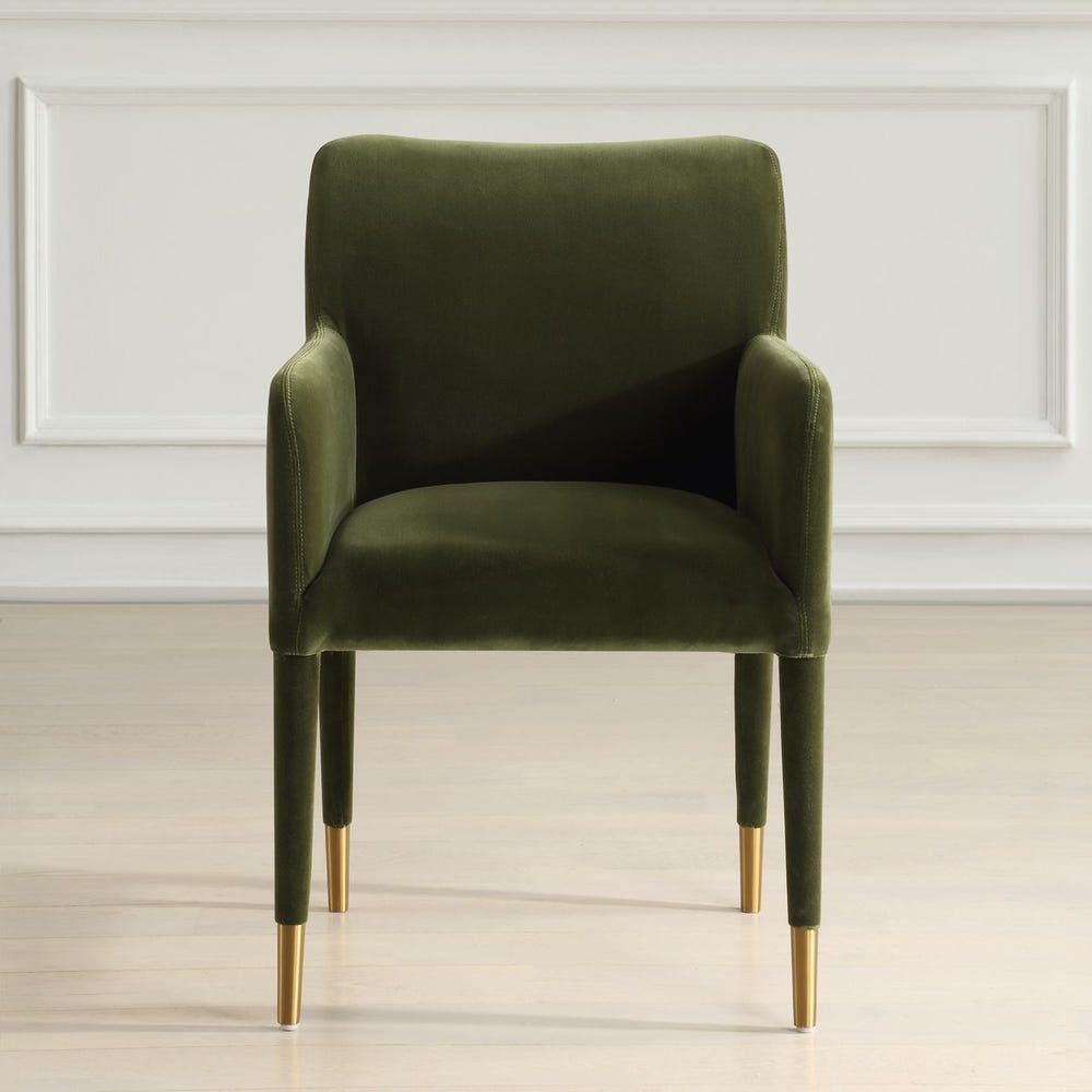 Moss green velvet dining arm chair with tailored silhouette and brushed brass leg caps, styled for modern elegant interiors.