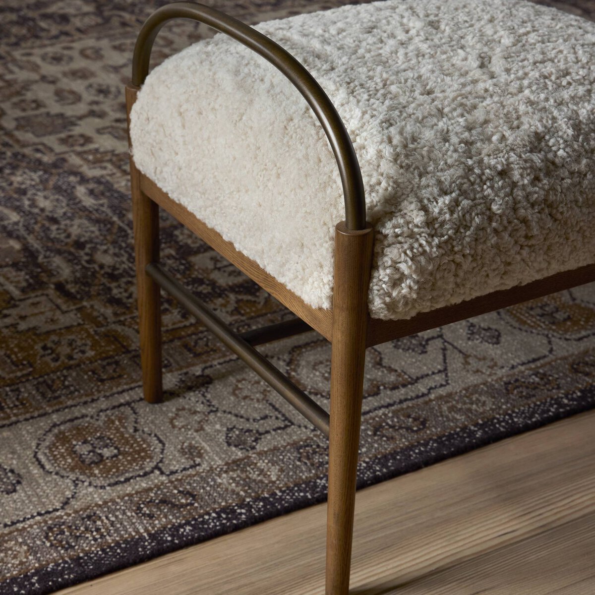Decorative shearling stool with textured cushion on a patterned rug