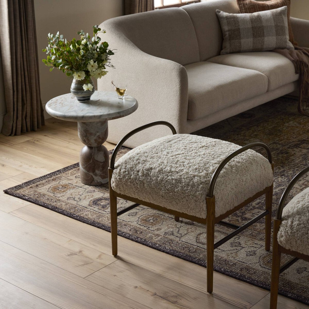 Living room with a beige sofa, marble side table, and cushioned ottoman.