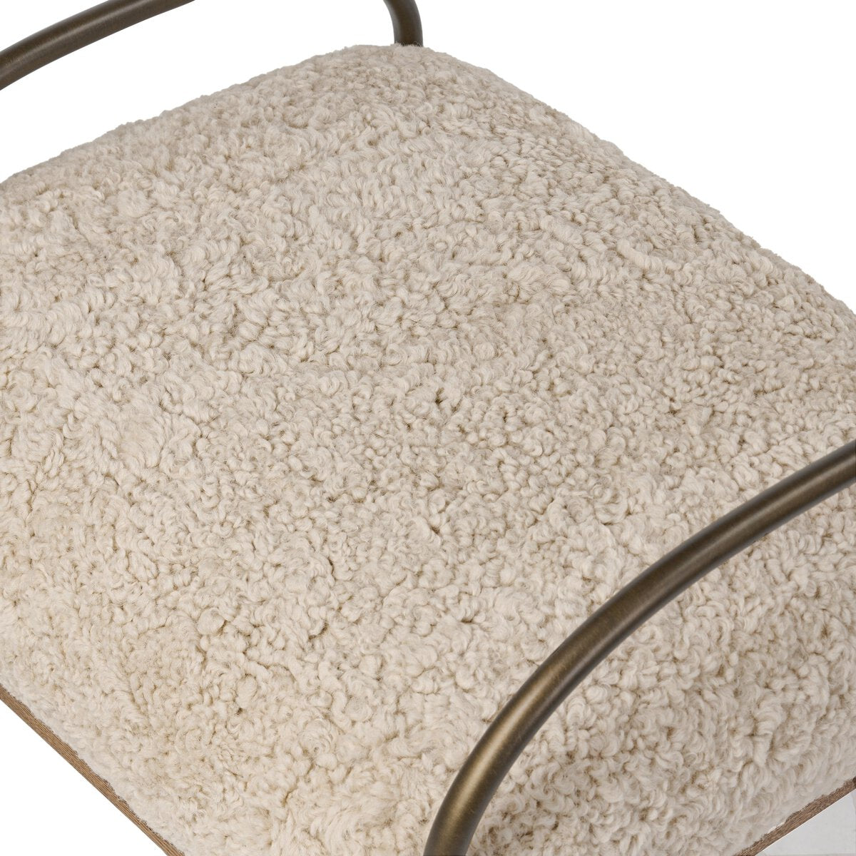 Close-up of a textured shearling cushion with a metal frame on a white background