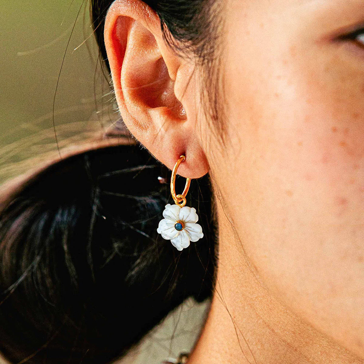 Hand-carved mother-of-pearl flower hoops in 18K gold-plated brass, glowing with movement, elegance, and seaside romance.