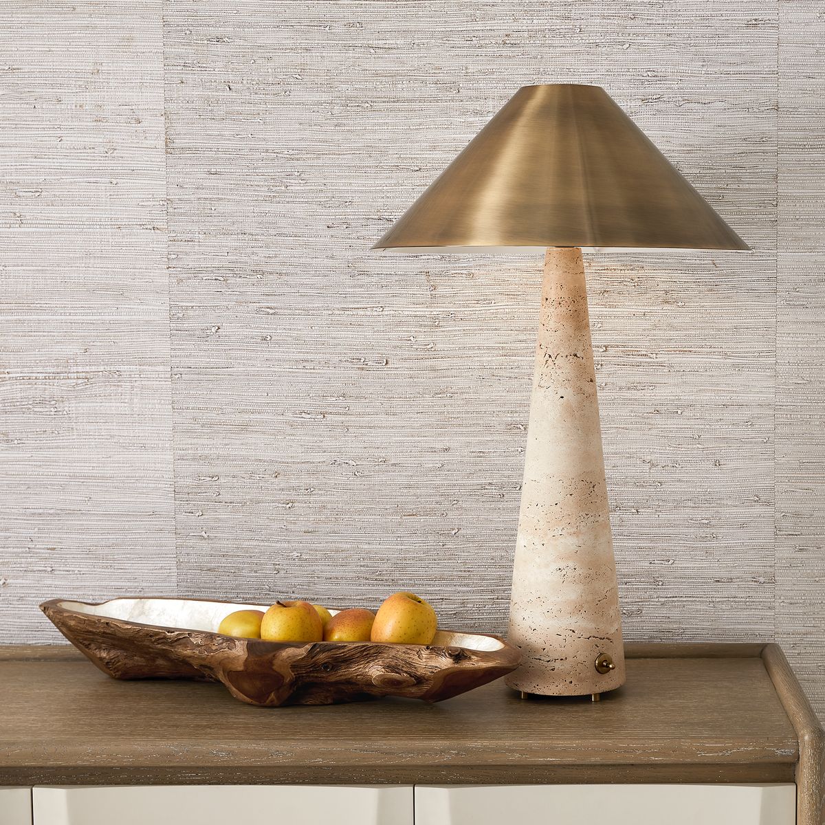 Monolith Table Lamp with honed beige travertine base and antique brass tapered shade, combining sculptural form with ambient lighting