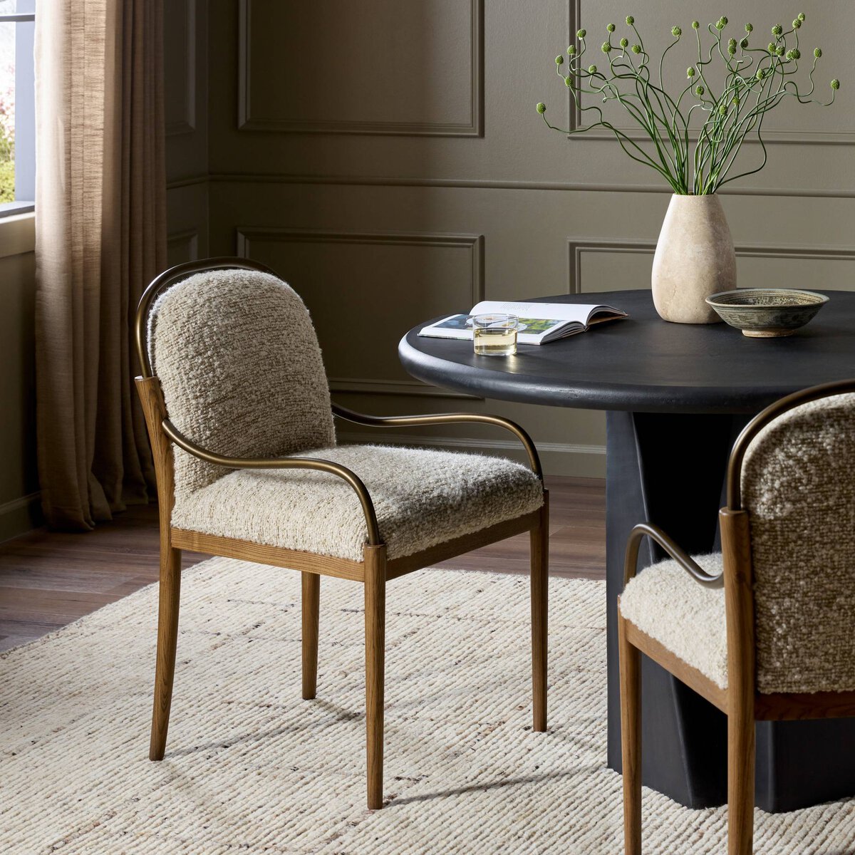 Curved upholstered dining chair in off white performance fabric with ash wood legs with a dining table