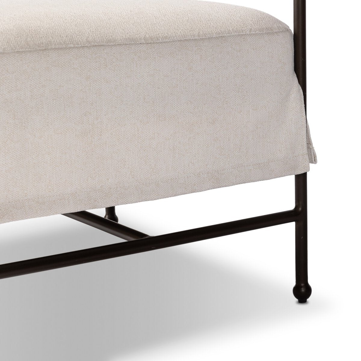 Outdoor lounge chair detail with curved matte gunmetal frame and handwoven linen-toned seat, styled for sculptural coastal living.