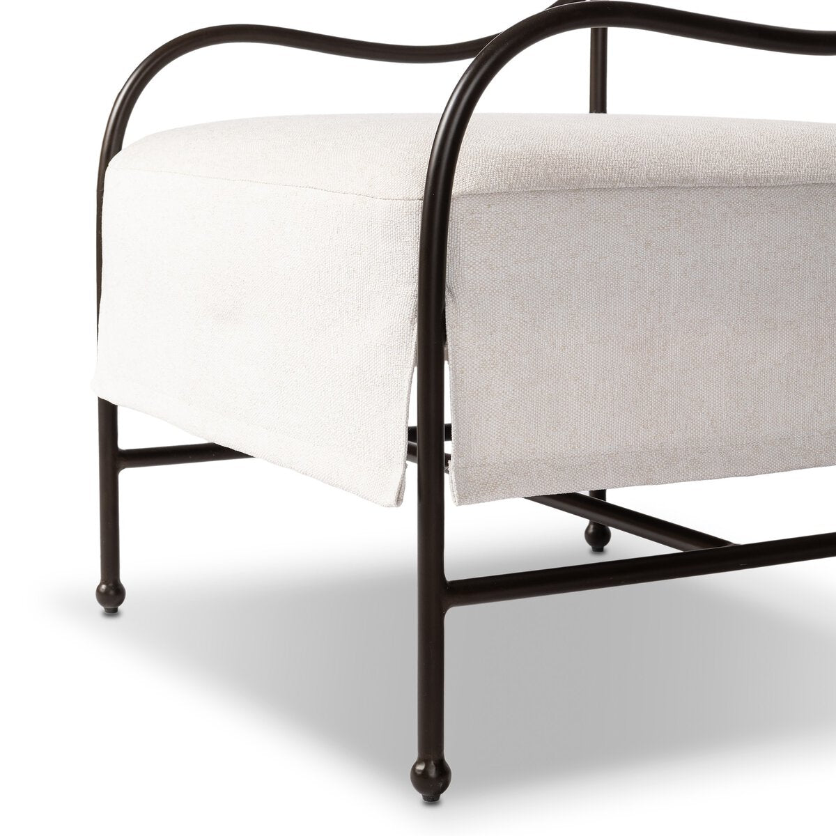 Outdoor lounge chair with curved matte gunmetal frame and handwoven linen-toned seat, styled for sculptural coastal living.
