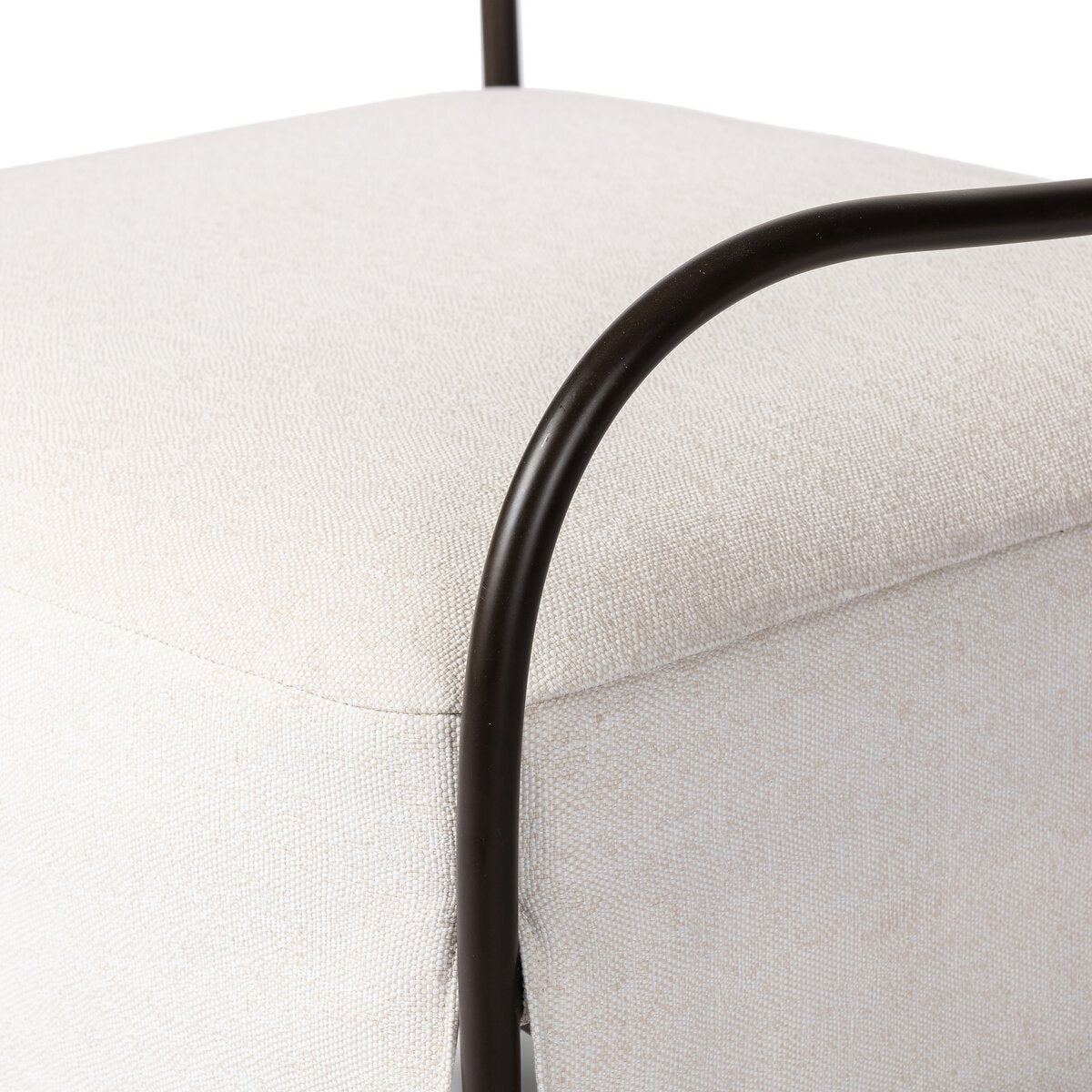 Outdoor lounge chair with curved matte gunmetal frame and handwoven linen-toned seat, styled for sculptural coastal living.