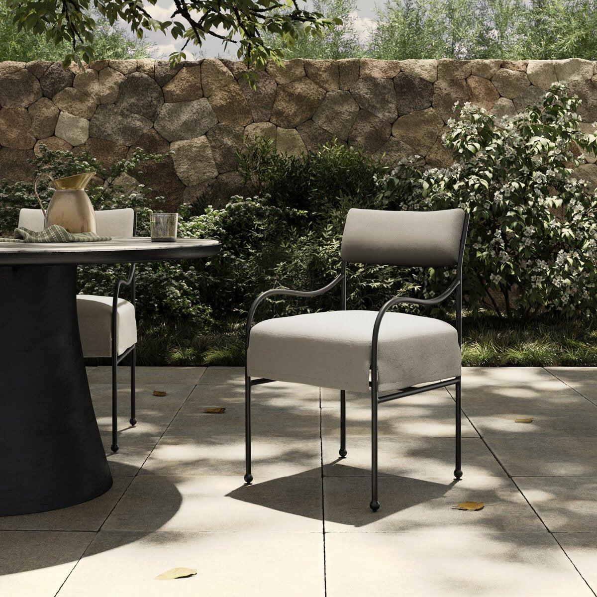 Sculptural outdoor dining chair with curved matte gunmetal frame and linen-toned all-weather weave, styled for refined alfresco dining.