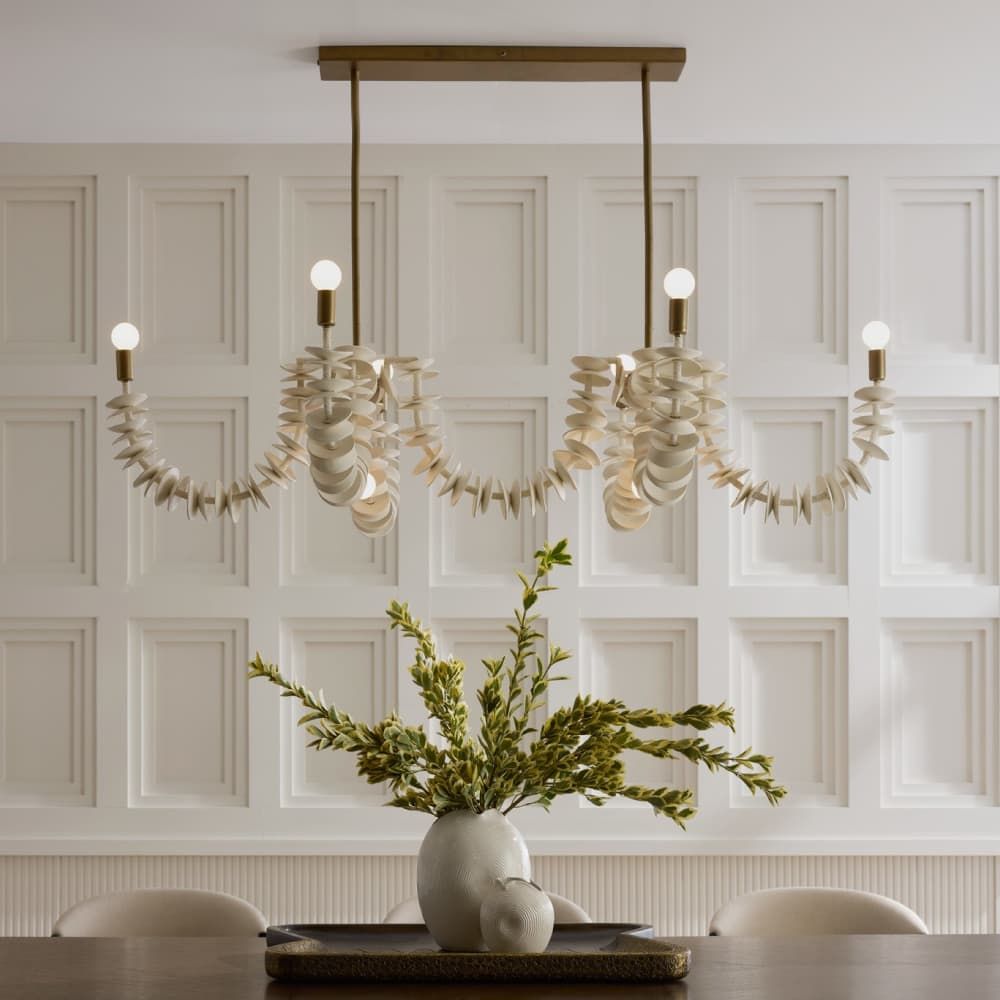 Ivory coconut shell chandelier with cascading strands and brass accents, offering sculptural coastal elegance for dining or entry spaces.