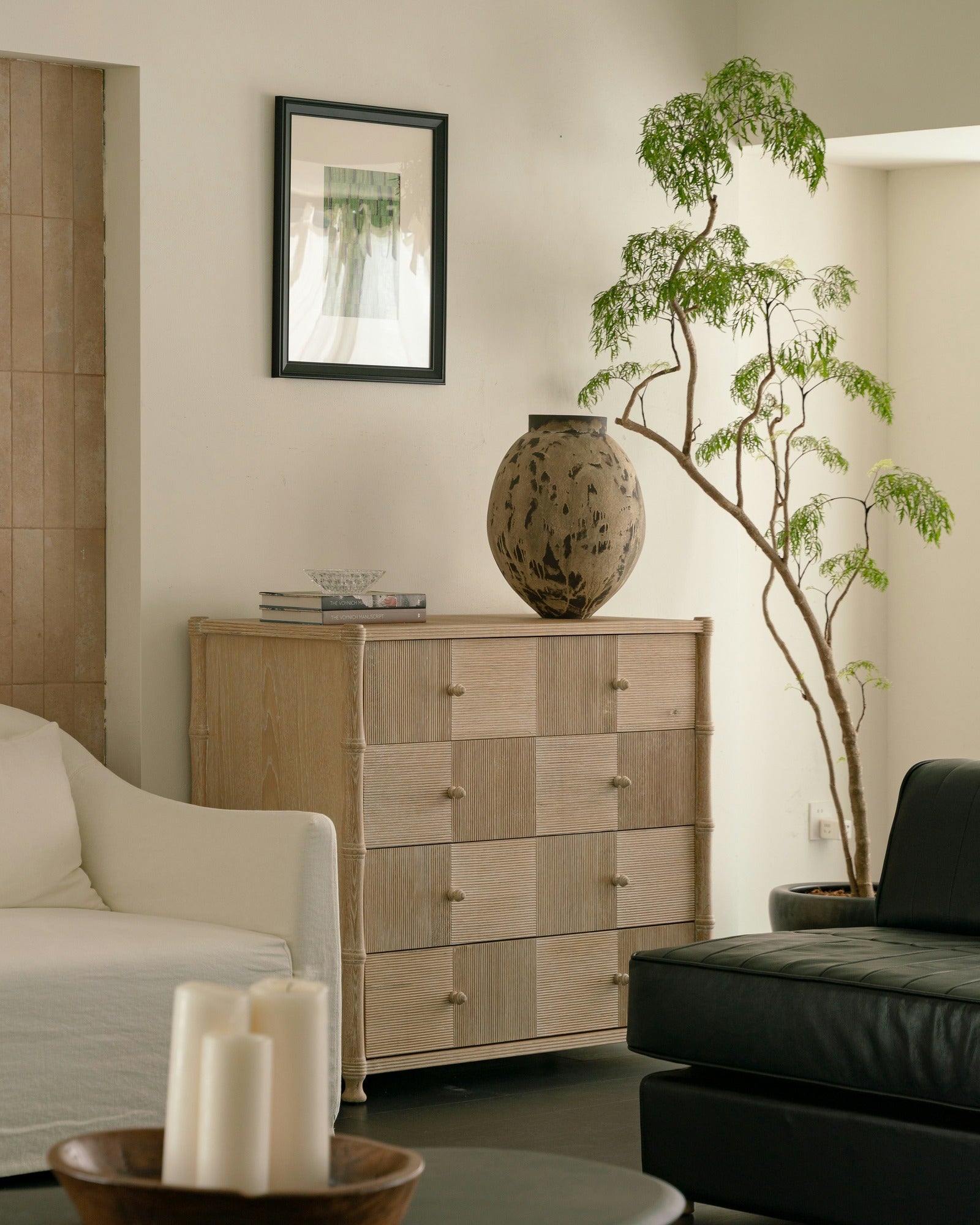 Warm neutral room with limestone tile wall, reeded oak chest, sculptural vase and olive tree — interior design consultation with Rachel Blindauer