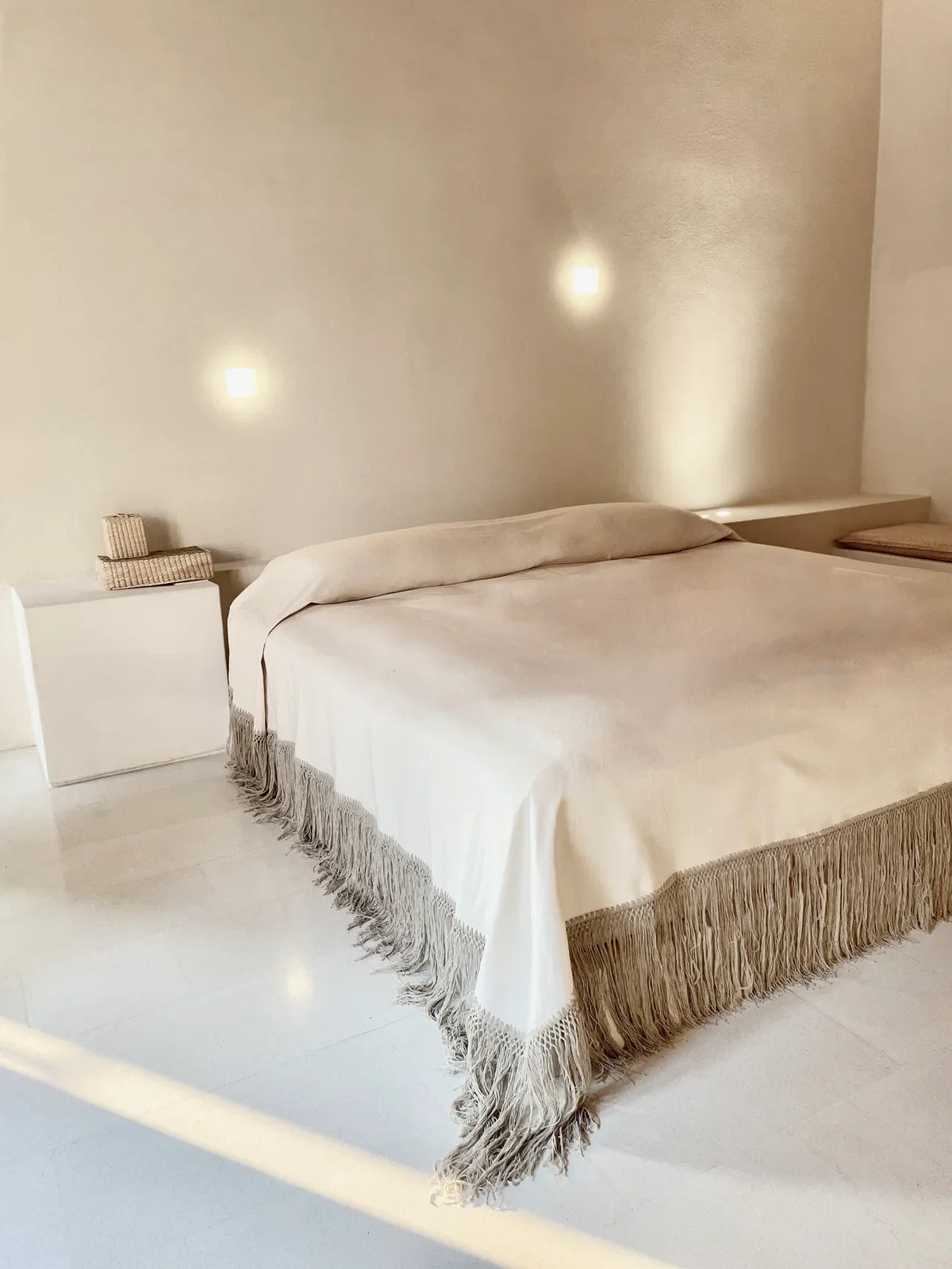Dune Handwoven Cotton Coverlet in putty styled on a bed in a warm plaster-walled bedroom