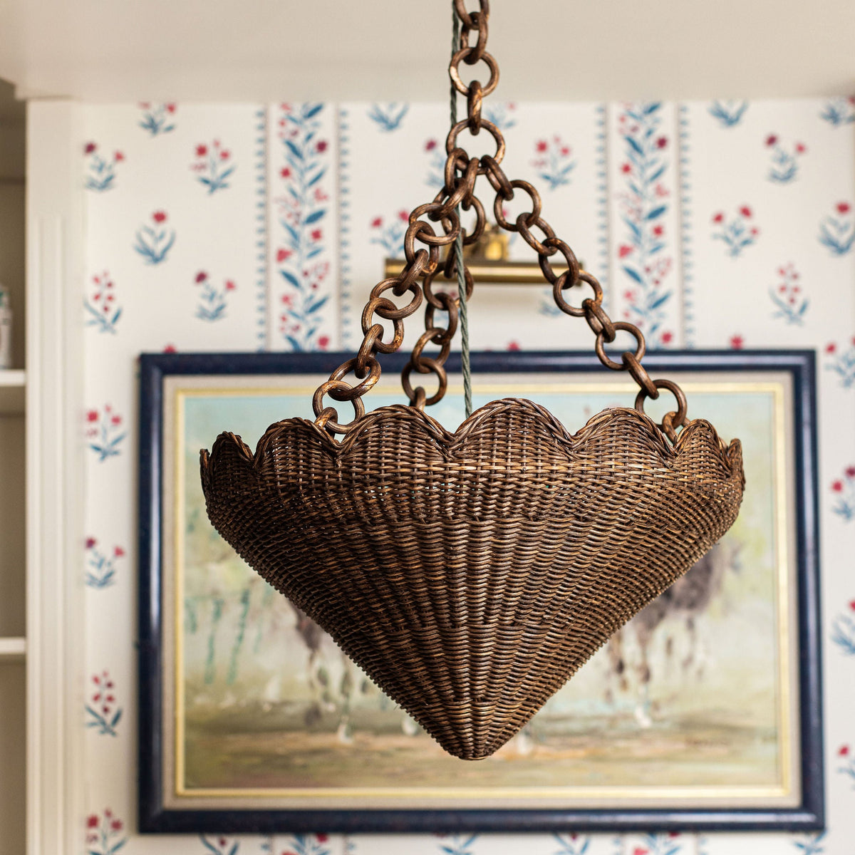 Scalloped rattan pendant hanging in front of a framed painting