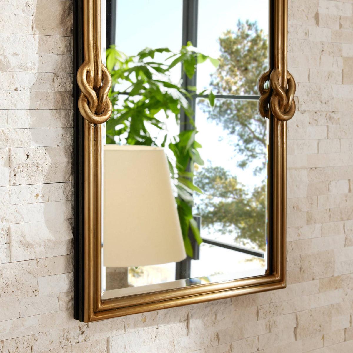 Antique brass rectangular mirror with knot accents reflecting a window