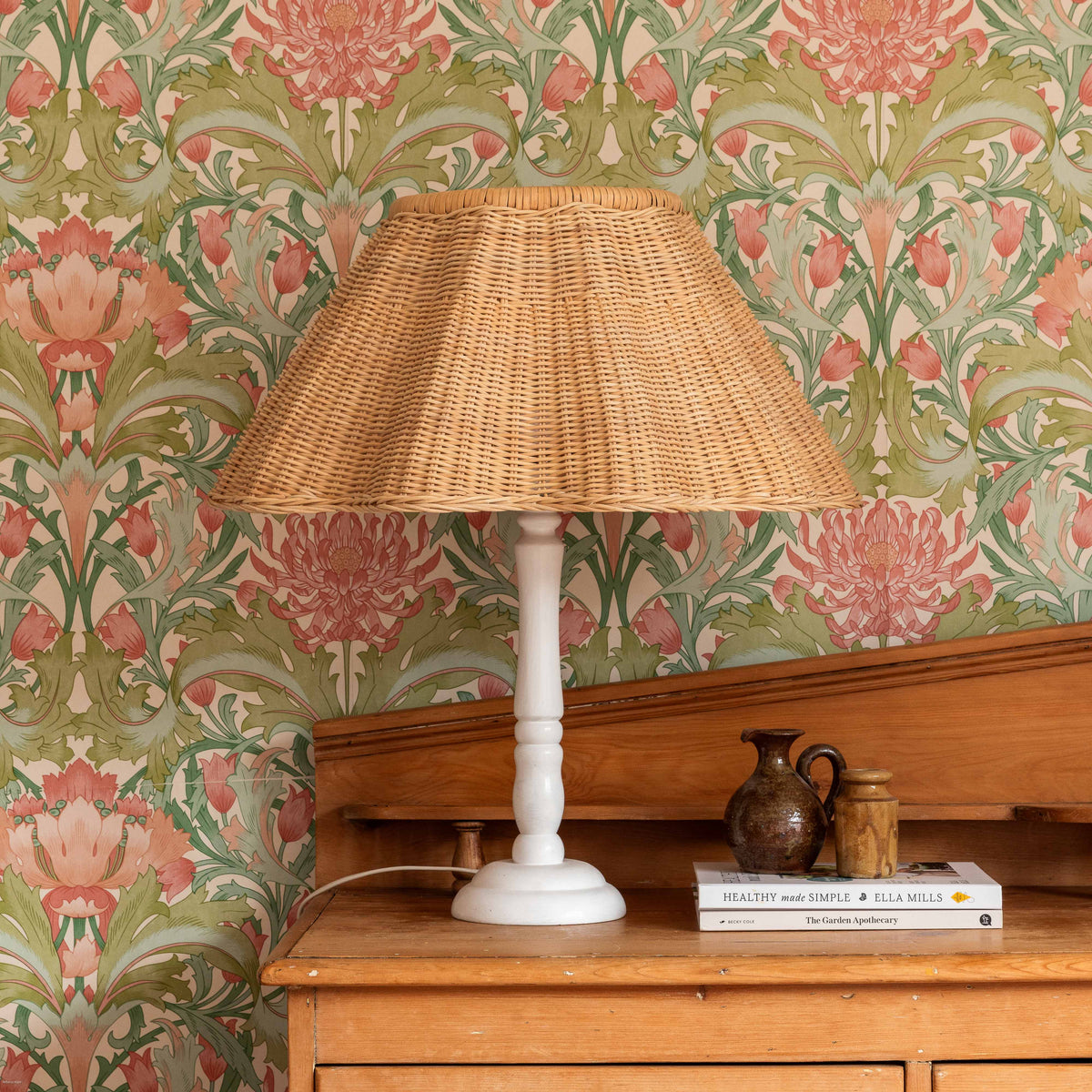 Ripple rattan lampshade on a table lamp against floral wallpaper