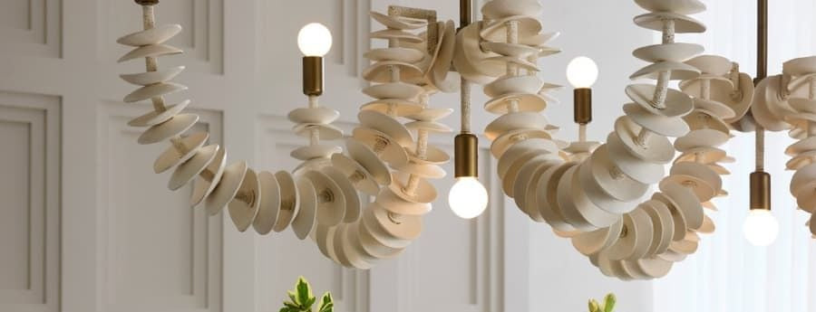 Tulum Tides Chandelier, ivory coconut shell spirals with brass fittings, styled against paneled wall molding with soft greenery below