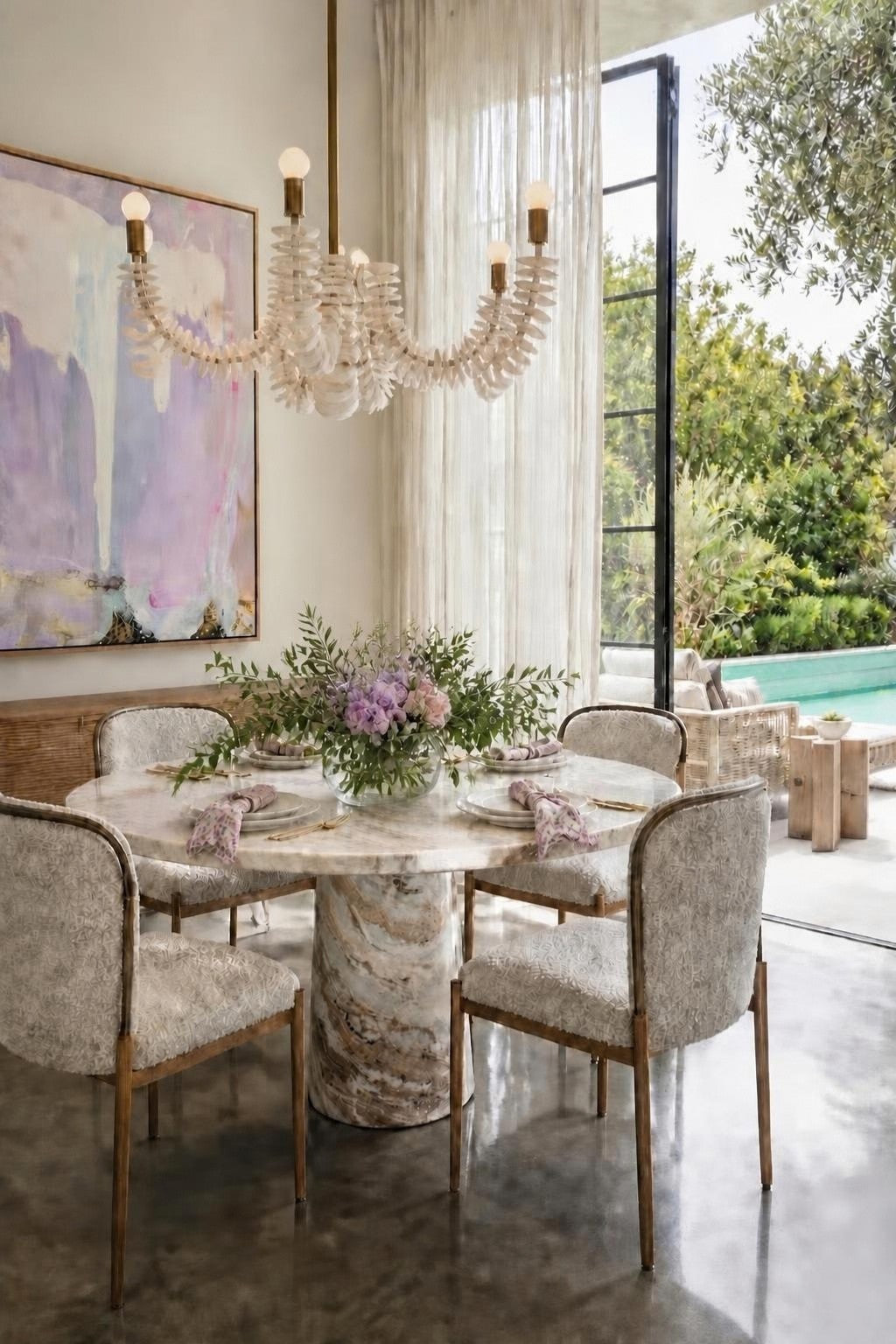 Bohemian Muse dining room designed by Rachel Blindauer: round marble table, upholstered chairs, shell chandelier and lavender abstract art