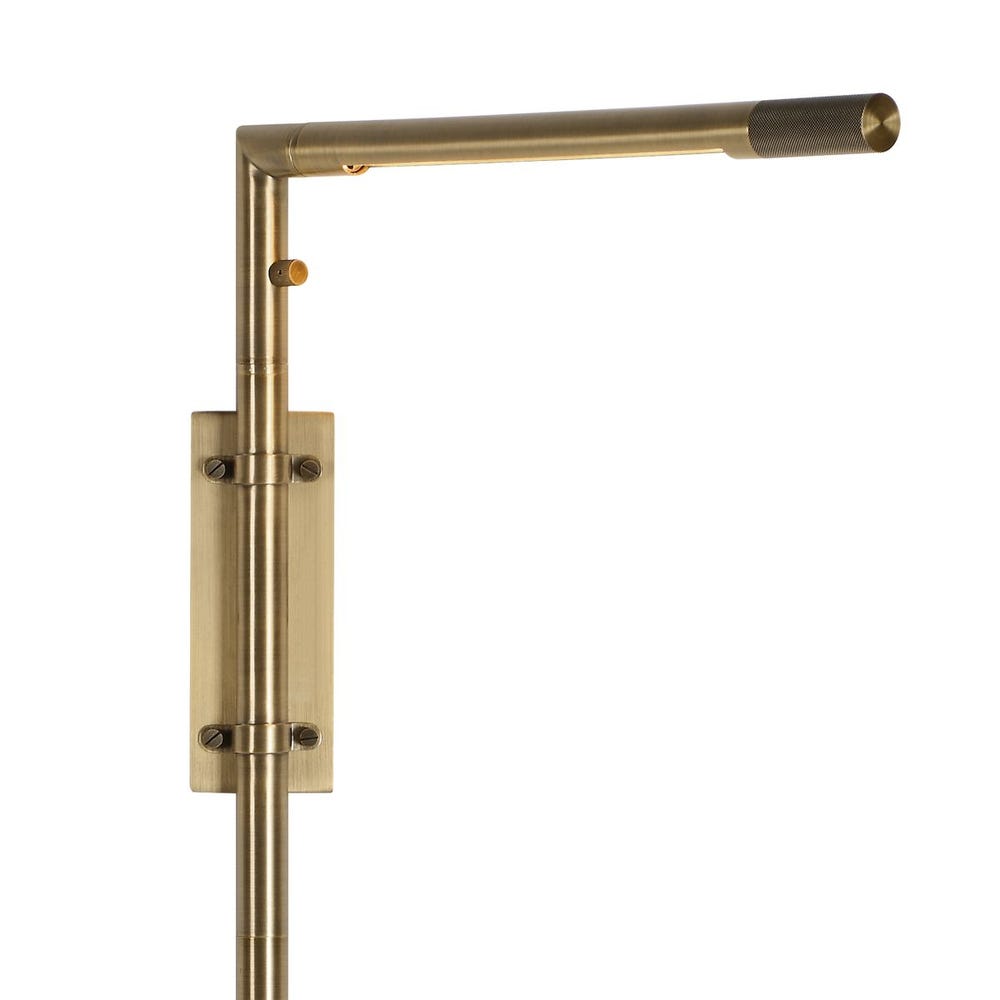 Antique brass wall sconce with adjustable rotating arm and integrated LED, styled in a minimalist reading nook for warm, directional lighting.