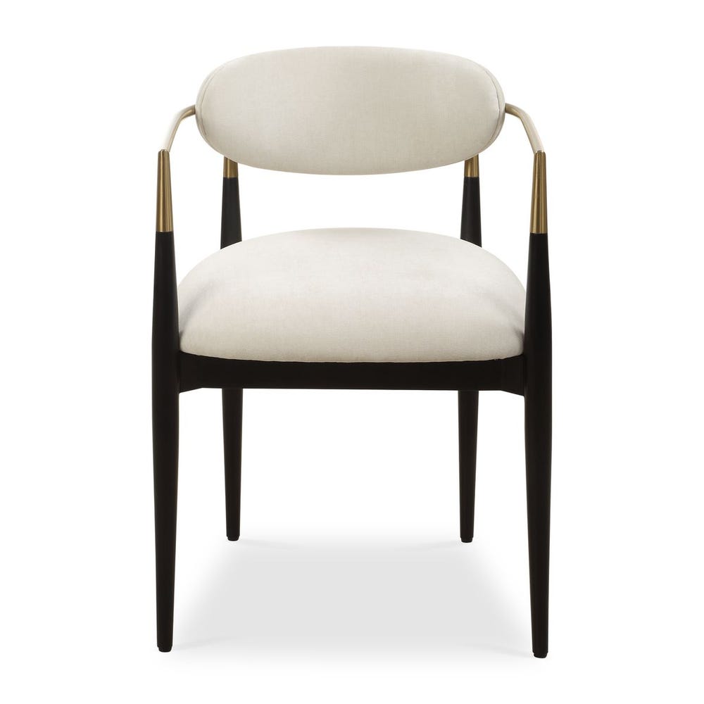 Mid-century modern dining armchair with off-white velvet upholstery, matte black wood legs, and brushed brass wraparound arms.