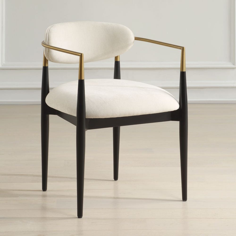 Chair with white cushioned seat and backrest, black legs, and brass armrests on a light wooden floor.