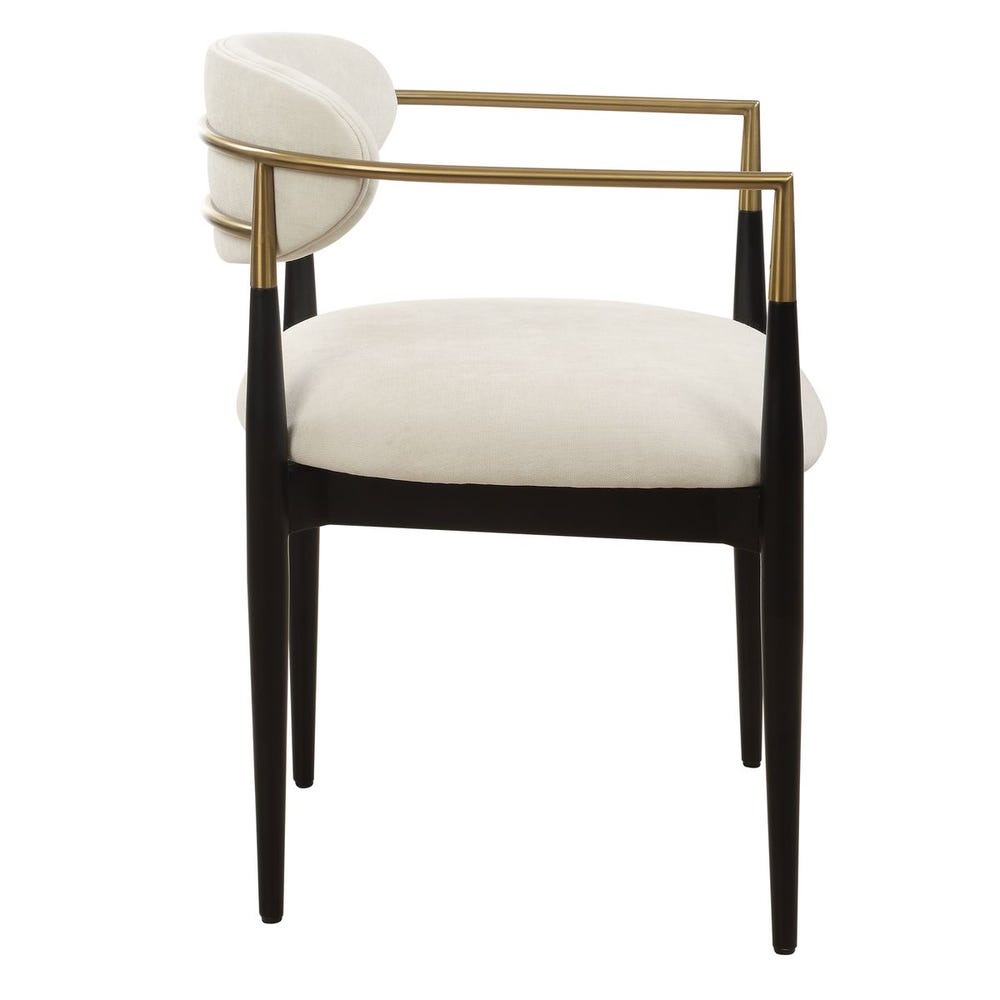 Mid-century modern dining armchair with off-white velvet upholstery, matte black wood legs, and brushed brass wraparound arms.