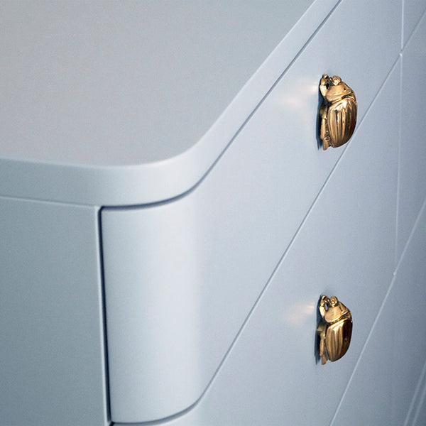 Light blue lacquered six-drawer chest with rounded corners and polished brass beetle knobs, ideal for modern, palm springs or mid-century inspired interiors.