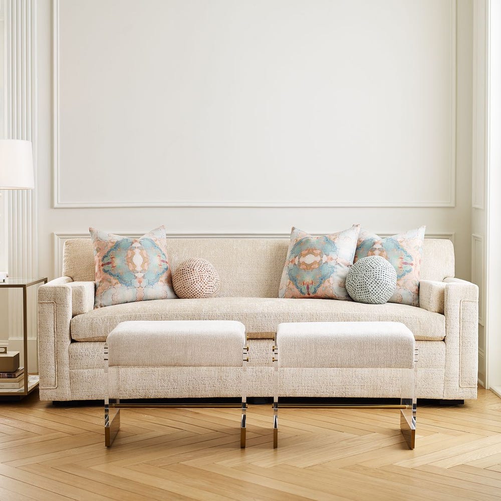 Round chenille ball pillow in sea salt and aqua dot pattern, styled on a beige sofa