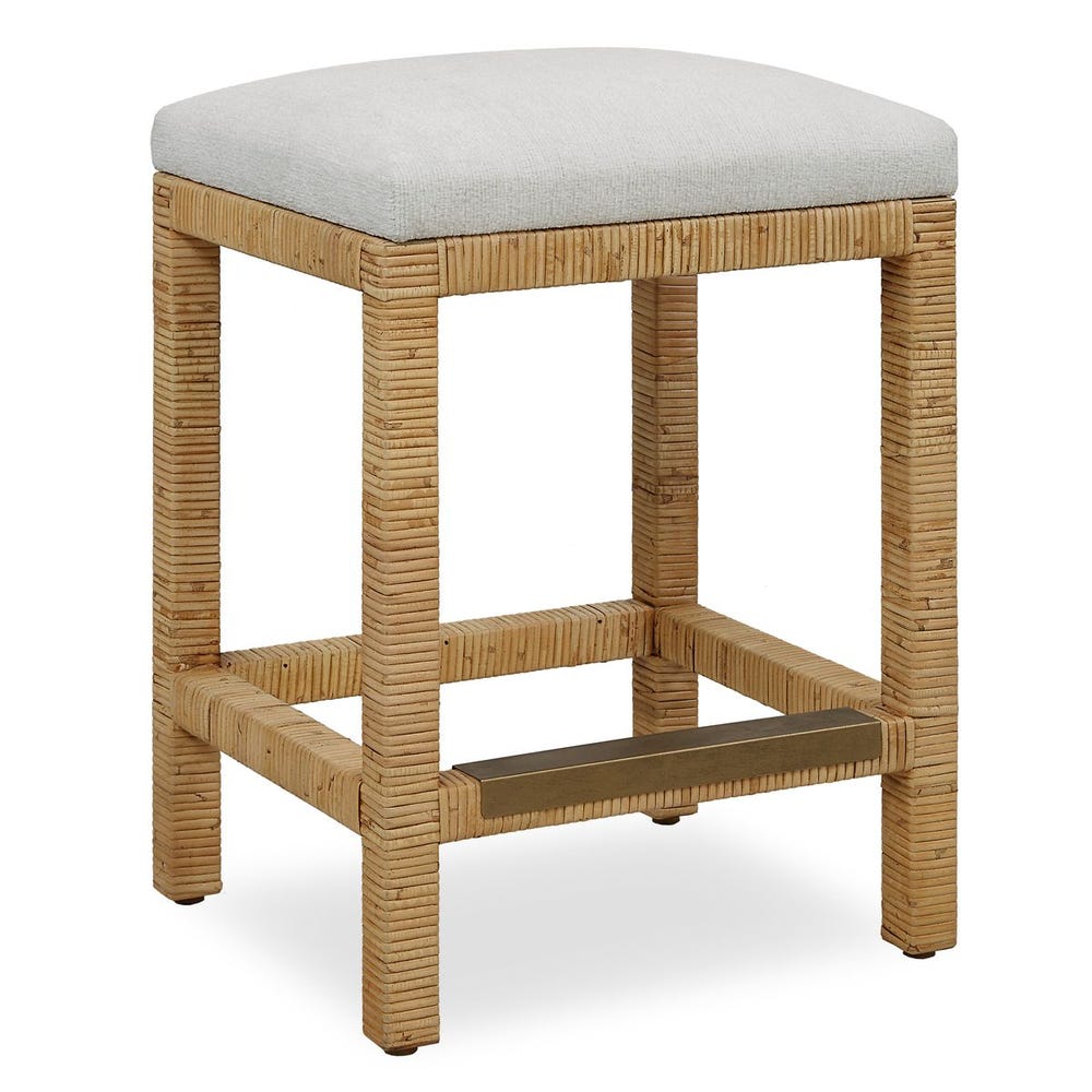 Handwoven rattan counter-height stool with off-white cushion and antique gold kickplate—coastal-inspired and refined.