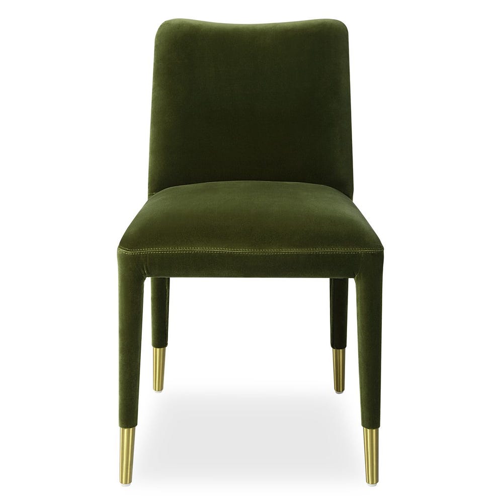 Armless tailored dining chair in emerald green velvet, featuring brushed brass ferrules and a sculptural silhouette.