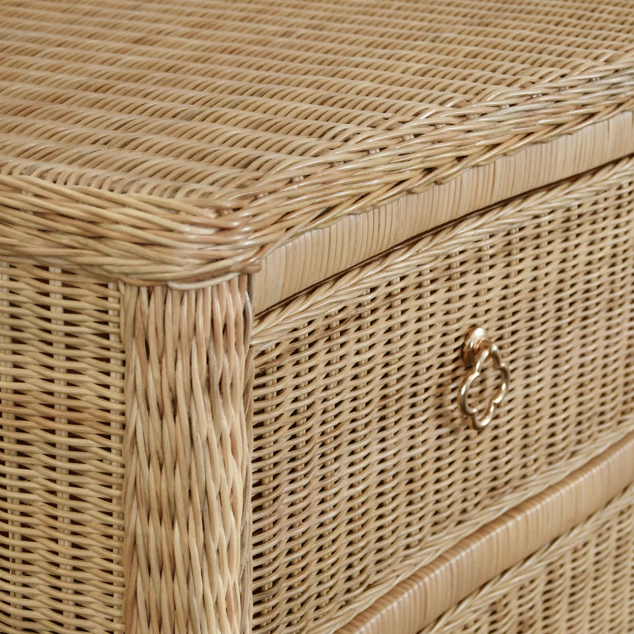 Woven rattan chest with four drawers, light wood frame, and satin brass pulls, ideal for bedroom, entryway, or coastal-inspired interiors.