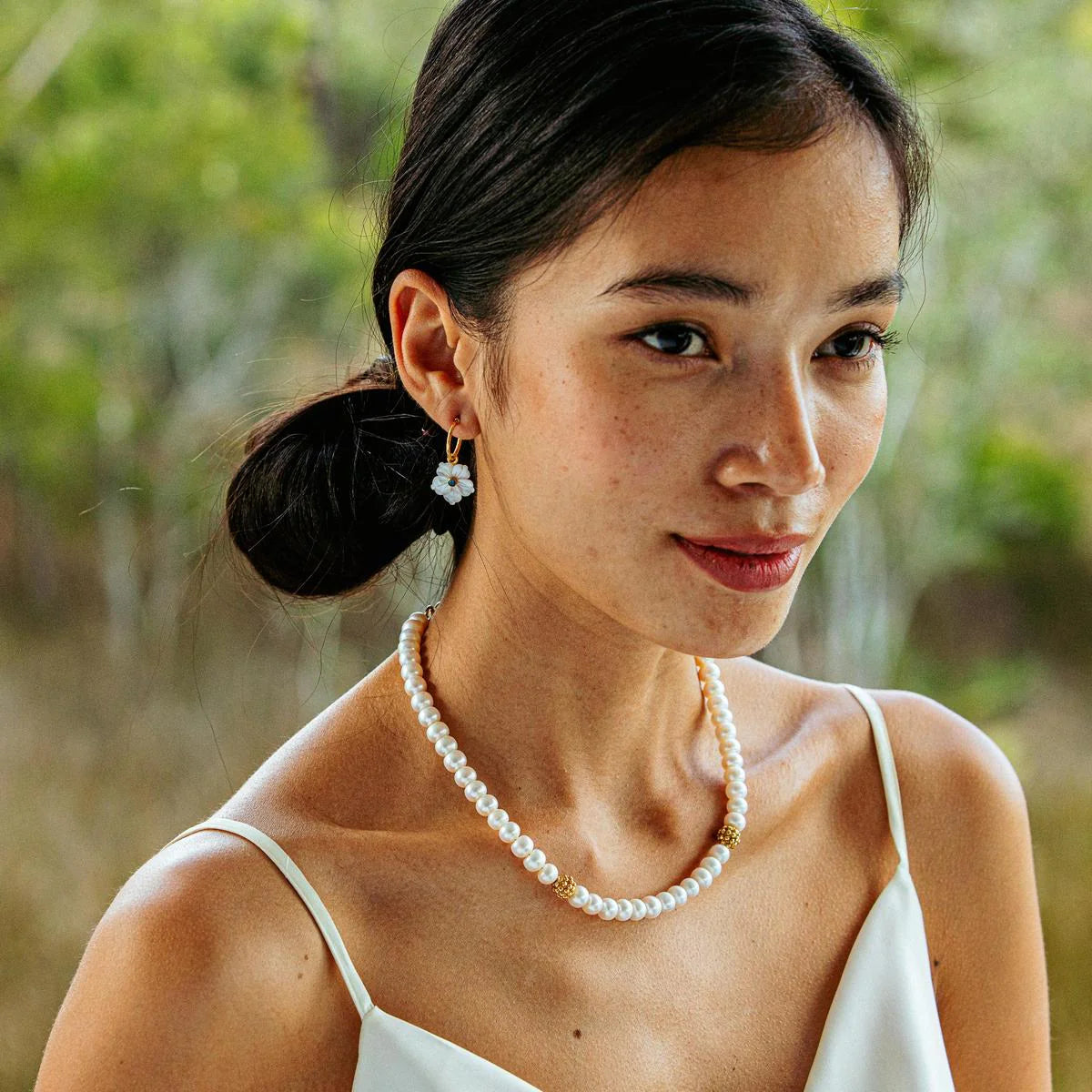 Hand-carved mother-of-pearl flower hoops in 18K gold-plated brass, glowing with movement, elegance, and seaside romance.