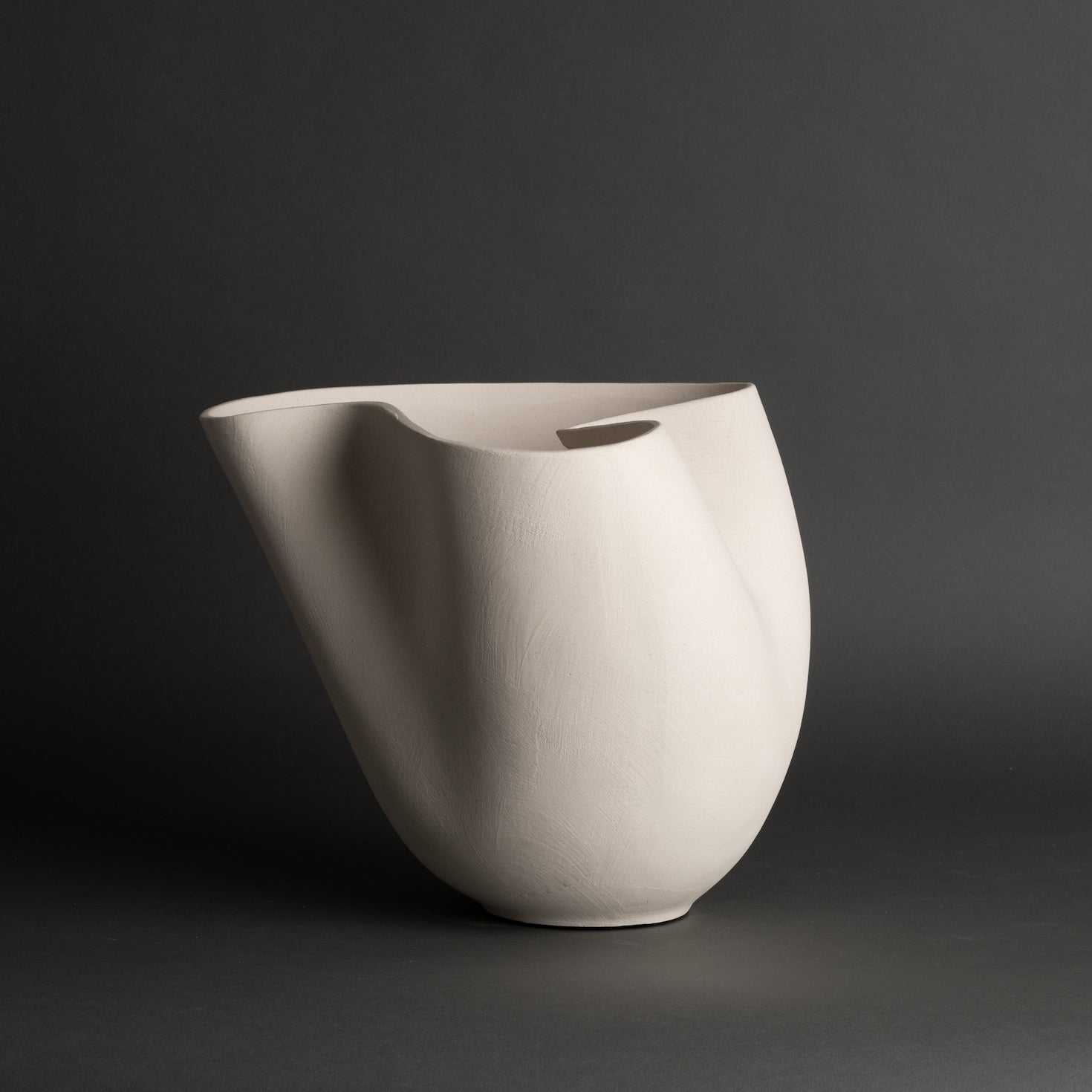 Off-white ceramic vase with an abstract sculptural silhouette, styled as a modern statement piece