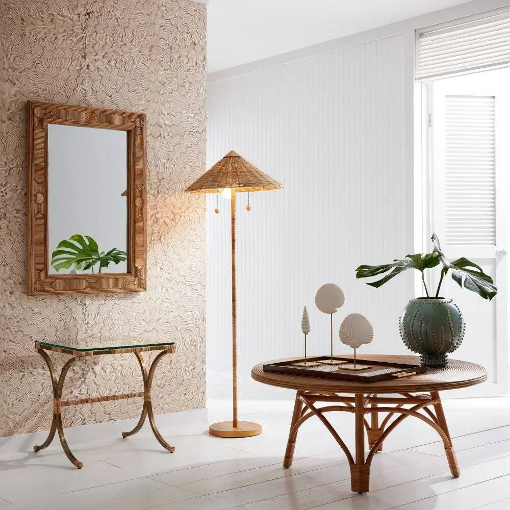 Tall rattan floor lamp in room with conical shade and antique brass base—coastal-inspired lighting with dual pull chains and warm, ambient glow.