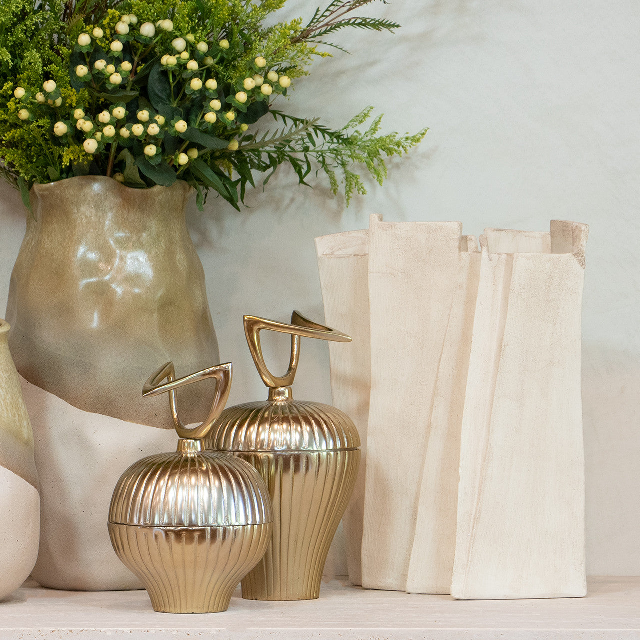 Modern sculptural vase in matte beige porcelain with folded ridges and rectangular form, styled as a standalone accent or with dried branches in minimalist interiors.