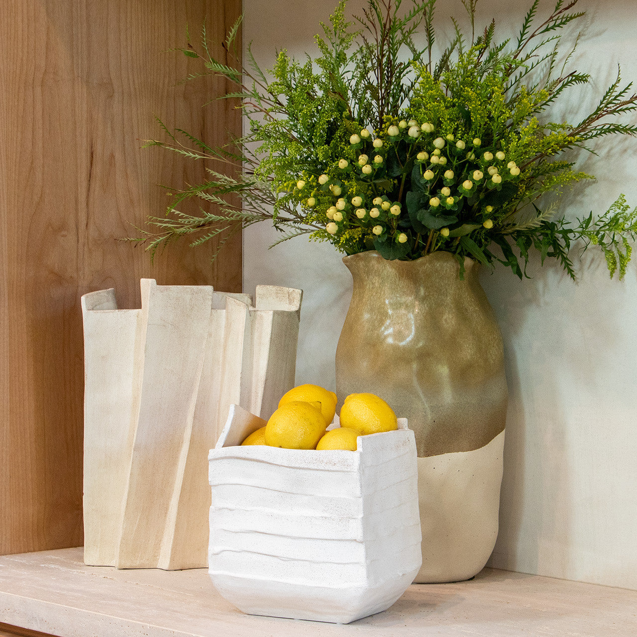 Modern sculptural vase in matte beige porcelain with folded ridges and rectangular form, styled as a standalone accent or with dried branches in minimalist interiors.