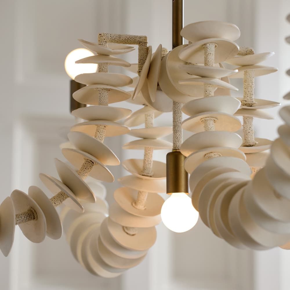 Ivory coconut shell chandelier with cascading strands and brass accents, offering sculptural coastal elegance for dining or entry spaces.