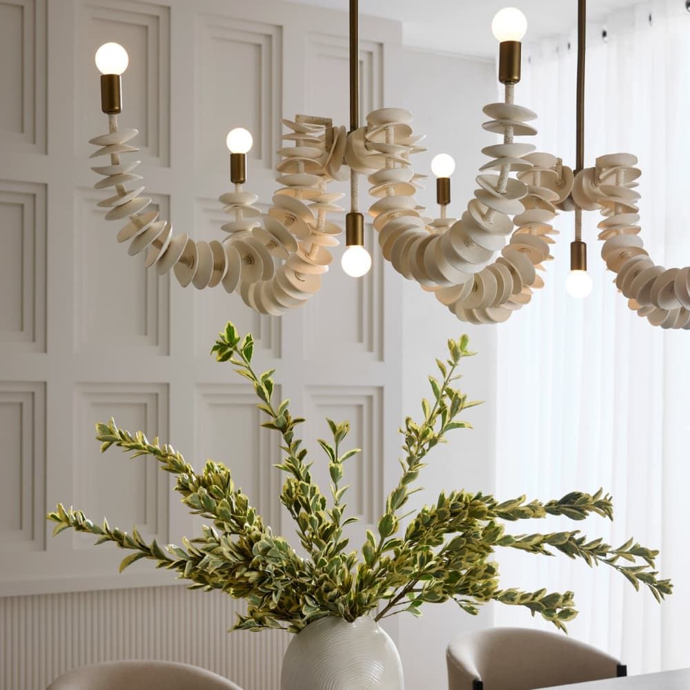 Ivory coconut shell chandelier with cascading strands and brass accents, offering sculptural coastal elegance for dining or entry spaces.