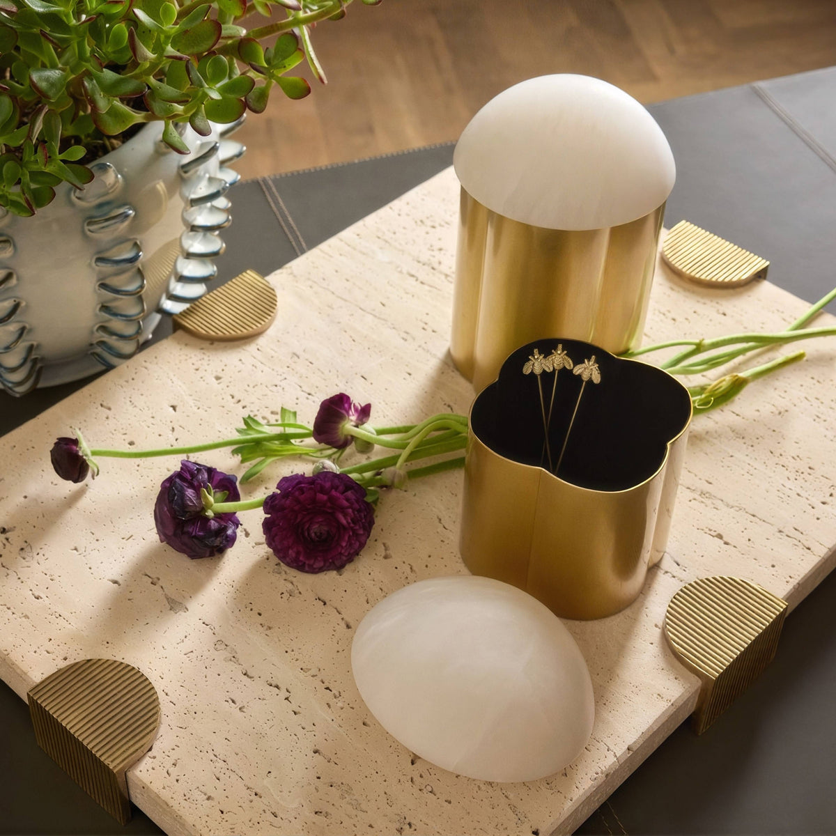Marble tray with brass clasps styled on a coffee table with flowers and brass boxes