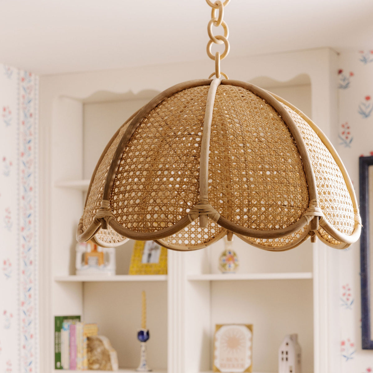 Scalloped cane dome pendant hanging in front of white shelves