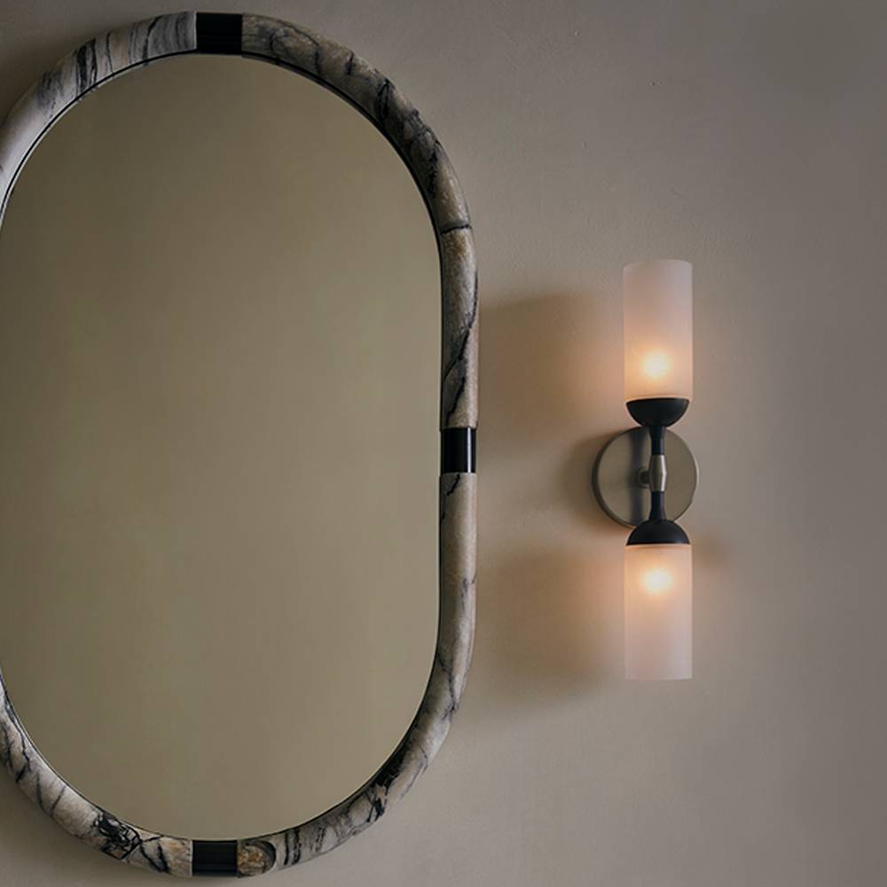 Marbled oval mirror beside a wall sconce