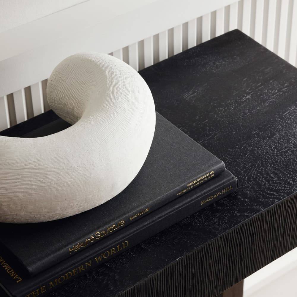Close-up of the white textured knot sculpture on a dark table