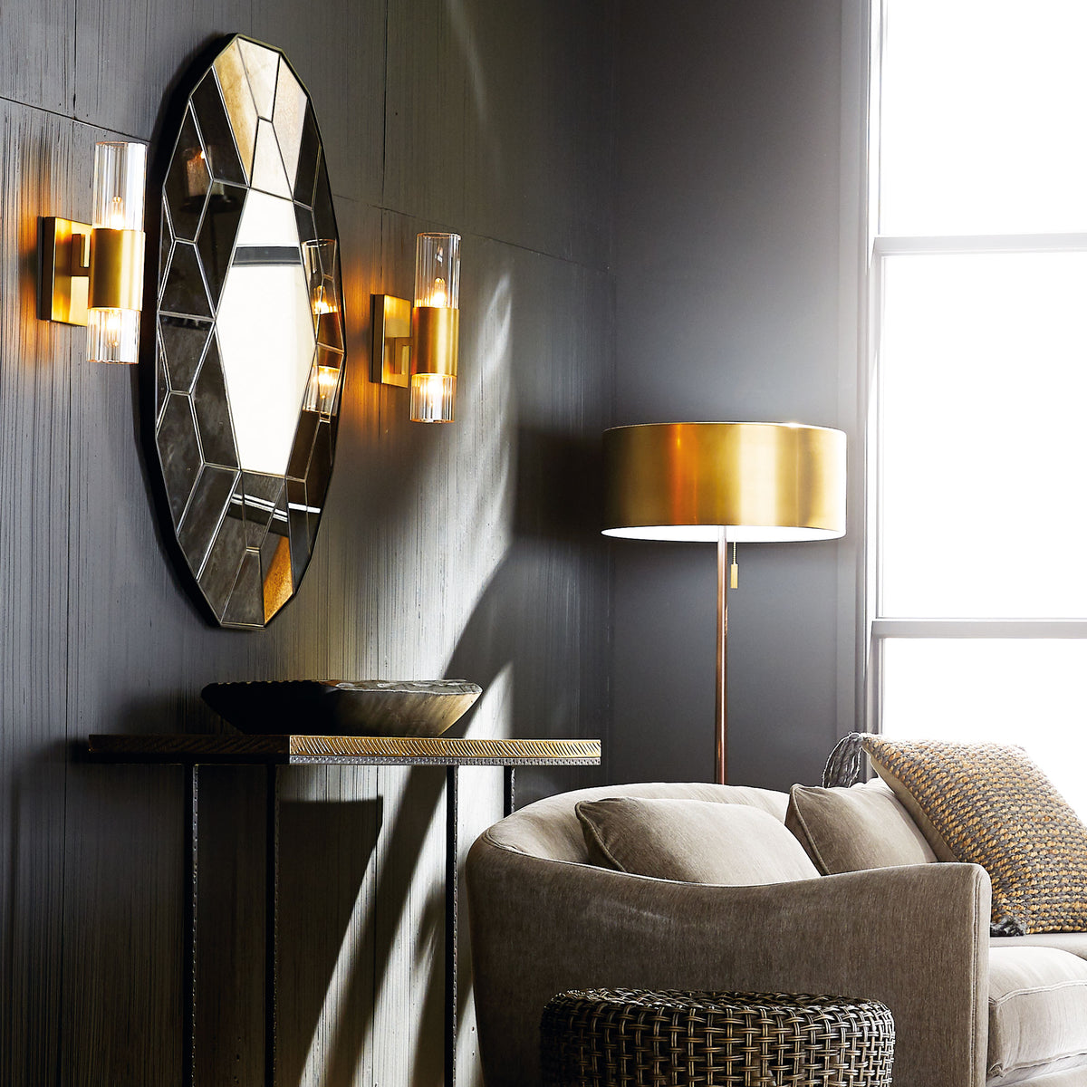 Faceted antiqued glass mirror above a console with brass sconces